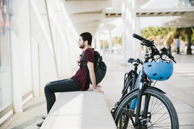 Uomo lateralmente seduto accanto alla bicicletta elettrica