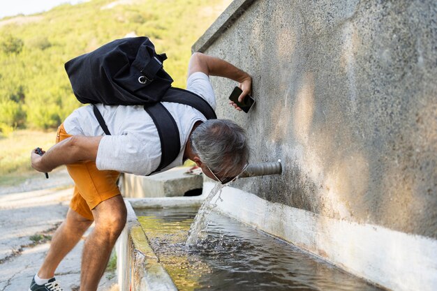 Uomo maggiore che beve acqua fresca