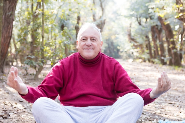 Uomo maggiore che fa yoga nel parco