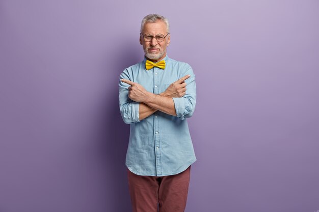 Uomo maggiore che indossa camicia blu e papillon giallo