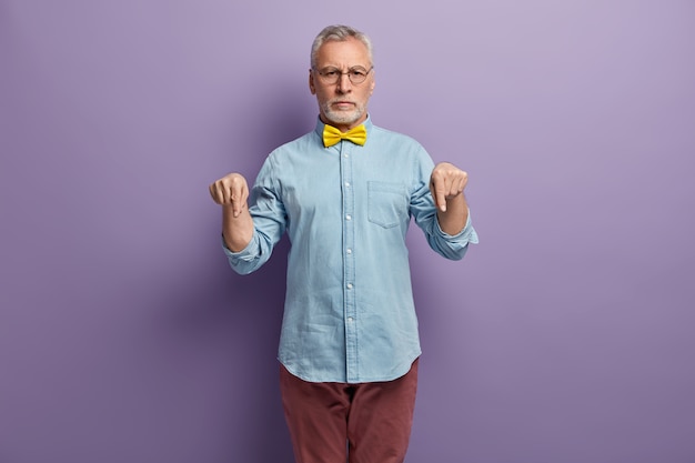 Uomo maggiore che indossa camicia blu e papillon giallo