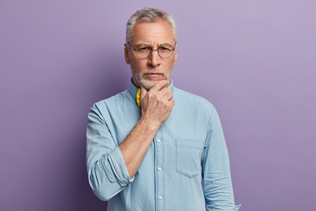 Uomo maggiore che indossa camicia blu e papillon giallo