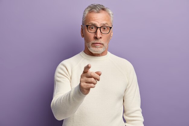 Uomo maggiore che indossa un maglione bianco e occhiali da vista alla moda