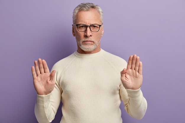 Uomo maggiore che indossa un maglione bianco e occhiali da vista alla moda