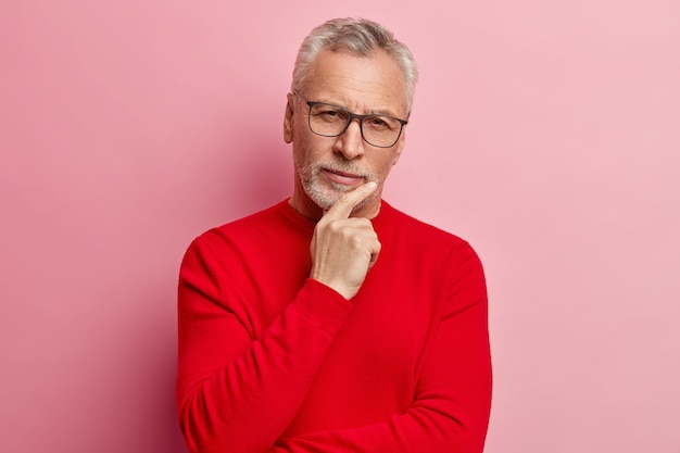 Uomo maggiore che indossa un maglione rosso e occhiali da vista alla moda