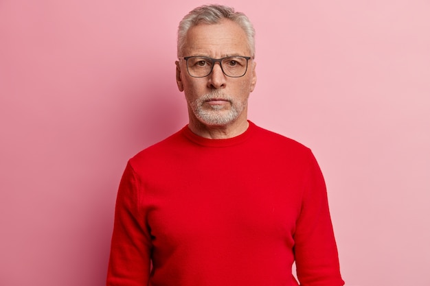 Uomo maggiore che indossa un maglione rosso e occhiali da vista alla moda