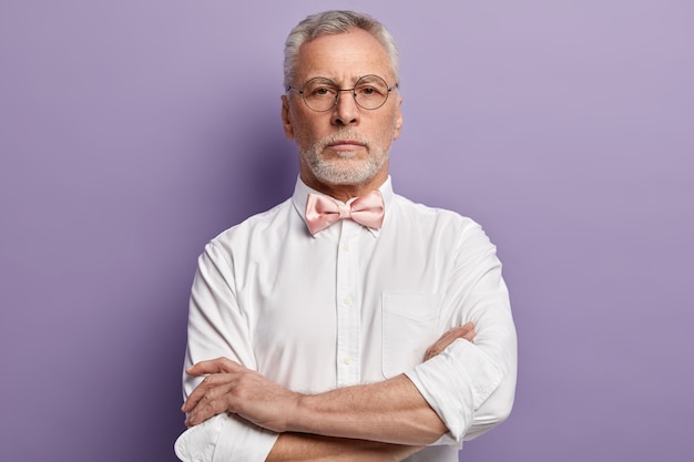 Uomo maggiore che indossa una camicia bianca e papillon rosa