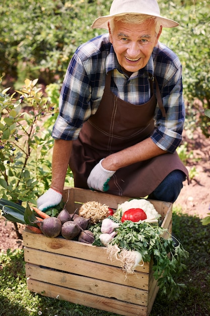 Uomo maggiore che lavora nel campo con i fiori