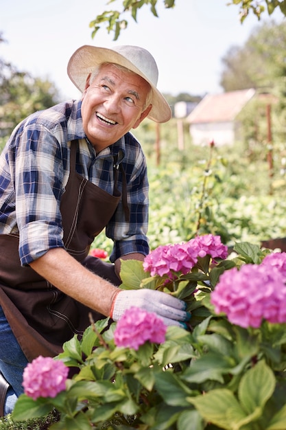 Uomo maggiore che lavora nel campo con i fiori