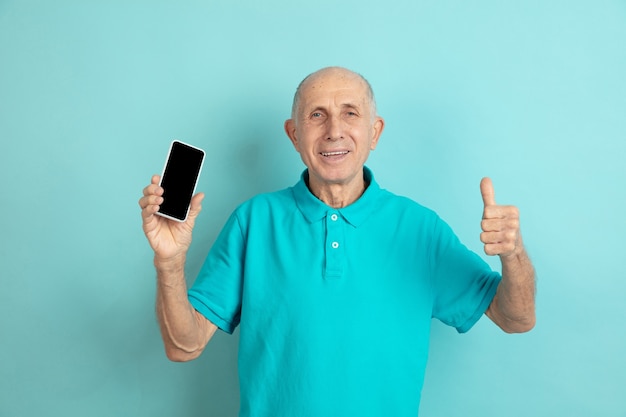 Uomo maggiore che mostra lo schermo del telefono in bianco