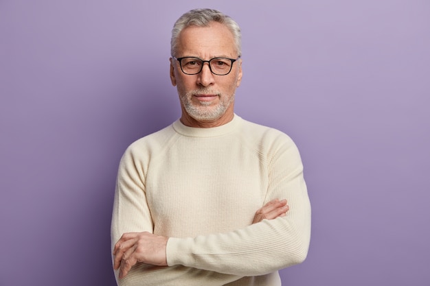 Uomo maggiore in maglione bianco e occhiali da vista