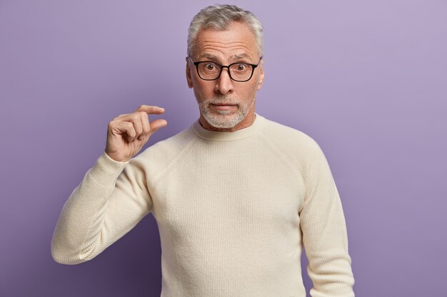 Uomo maggiore in maglione bianco e occhiali da vista