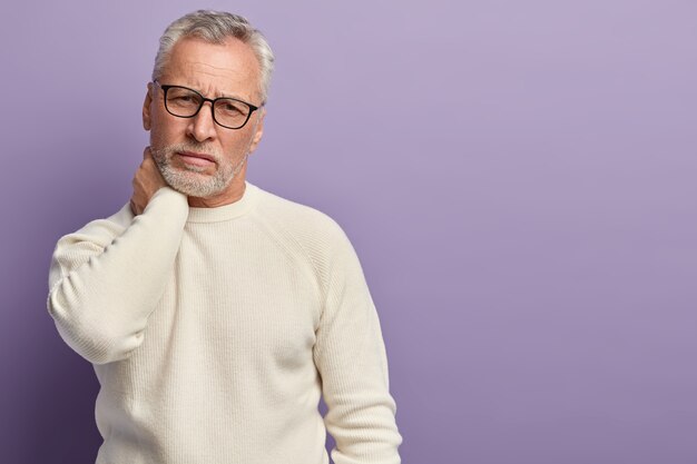 Uomo maggiore in maglione bianco e occhiali da vista