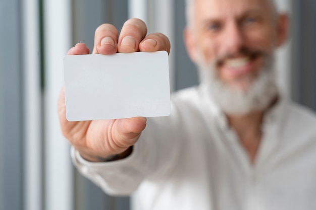 Uomo maggiore sorridente che tiene biglietto da visita in bianco