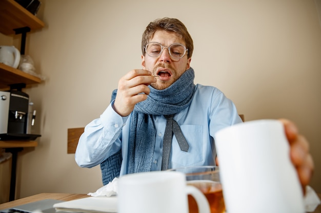 Uomo malato mentre lavorava in ufficio, uomo d'affari preso raffreddore, influenza stagionale.