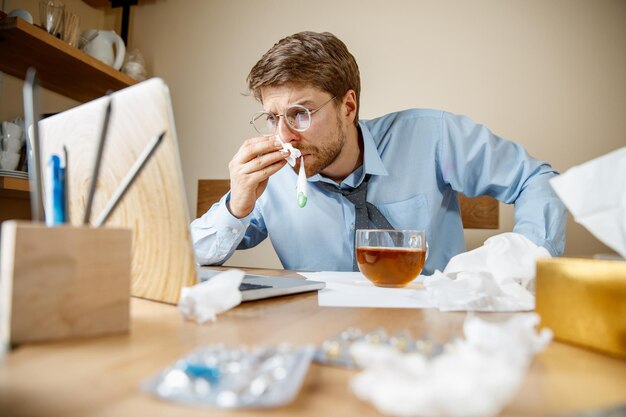 Uomo malato mentre lavorava in ufficio, uomo d'affari preso raffreddore, influenza stagionale.