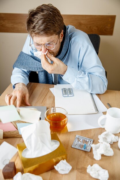 Uomo malato mentre lavorava in ufficio, uomo d'affari preso raffreddore, influenza stagionale.