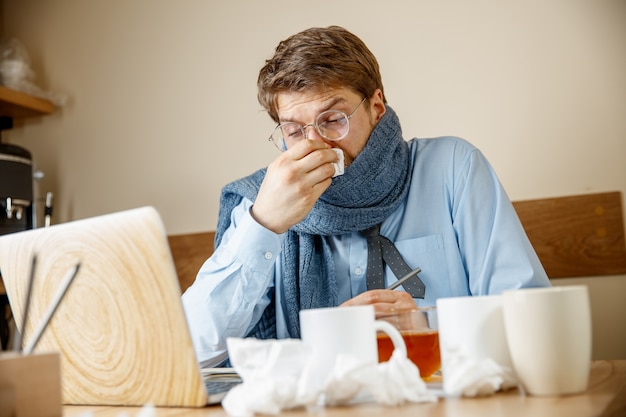 Uomo malato mentre lavorava in ufficio, uomo d'affari preso raffreddore, influenza stagionale.