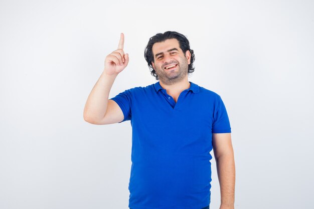 Uomo maturo che alza il dito indice in maglietta blu