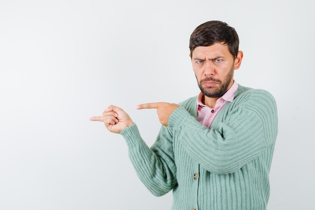 Uomo maturo che punta a sinistra in camicia, cardigan e sembra scontroso, vista frontale.