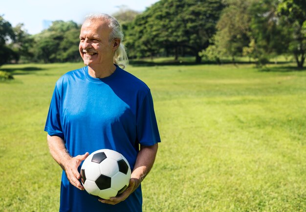 Uomo maturo che tiene un calcio