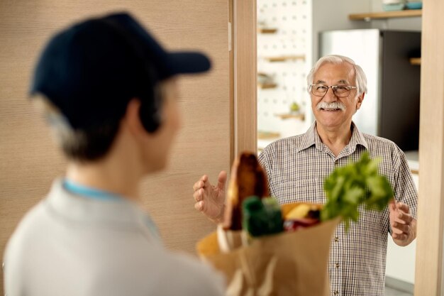 Uomo maturo felice che riceve la consegna di generi alimentari a casa