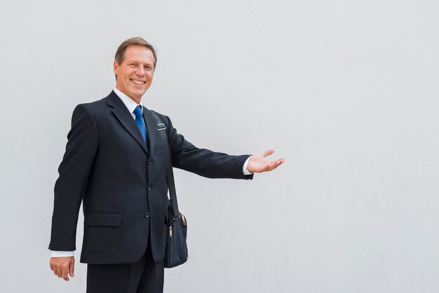 Uomo maturo sorridente che fa gesto di mano su fondo bianco