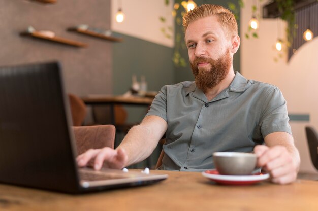 Uomo moderno bello che lavora accanto a una tazza di caffè