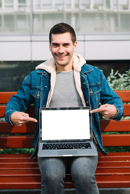 Uomo moderno che si siede sul banco con modello di laptop