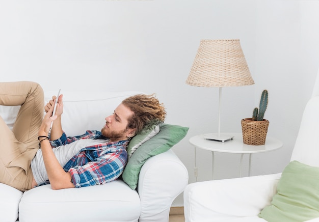 Uomo moderno che utilizza la tabella sul divano