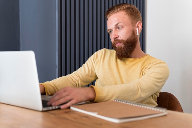 Uomo moderno con auricolari che lavorano a casa