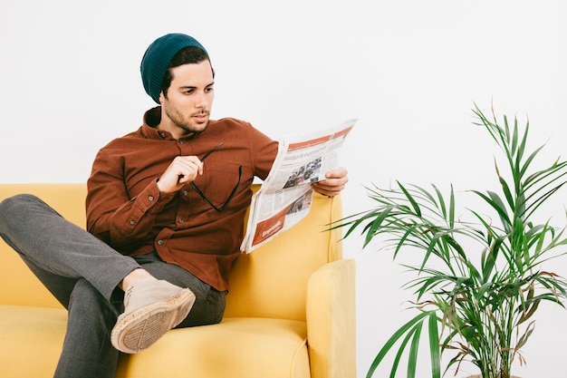 Uomo moderno con giornale sul divano