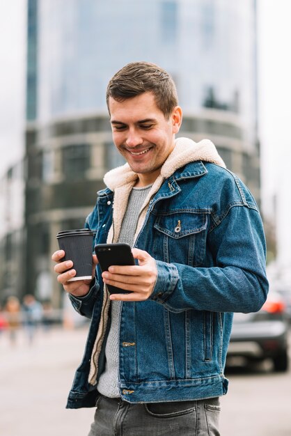 Uomo moderno con la tazza di caffè in ambiente urbano