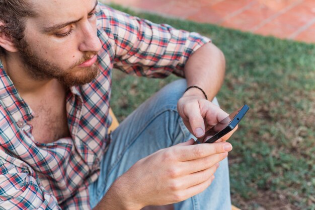 Uomo moderno con lo smartphone in giardino