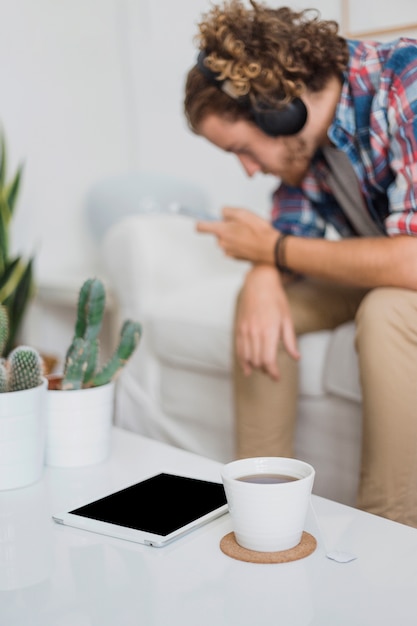 Uomo moderno con smartphone sul divano