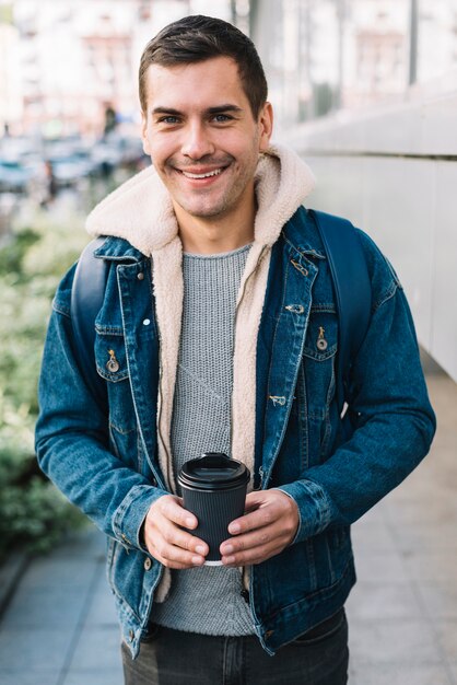 Uomo moderno con una tazza di caffè in ambiente urbano