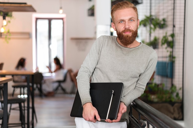 Uomo moderno del colpo medio che tiene il suo laptop e taccuino