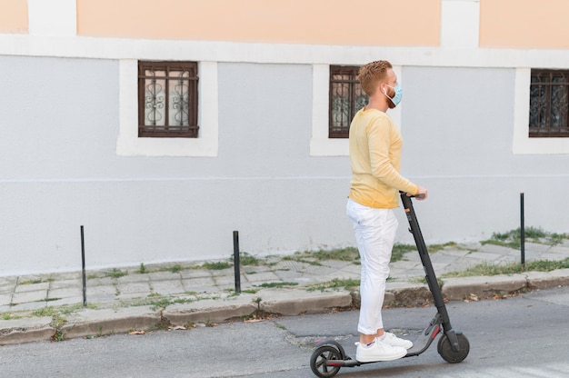 Uomo moderno di vista laterale che guida il suo scooter con lo spazio della copia