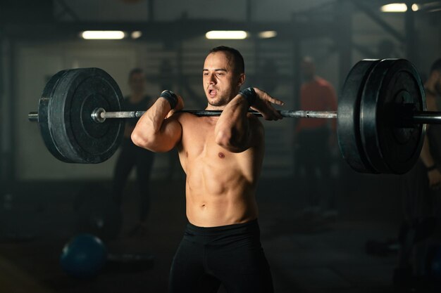 Uomo muscolare che solleva bilanciere sull'allenamento della forza in una palestra