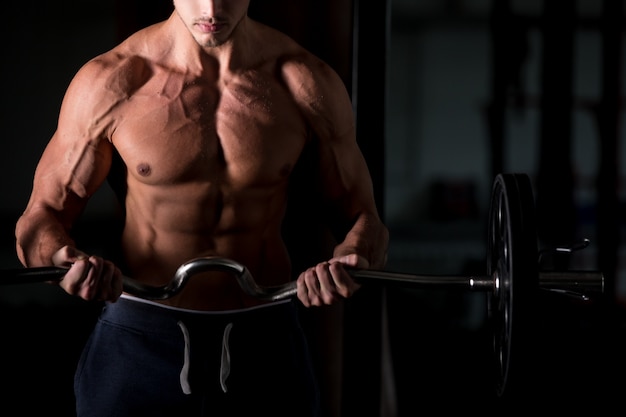 Uomo muscolare sollevando un bilanciere in palestra