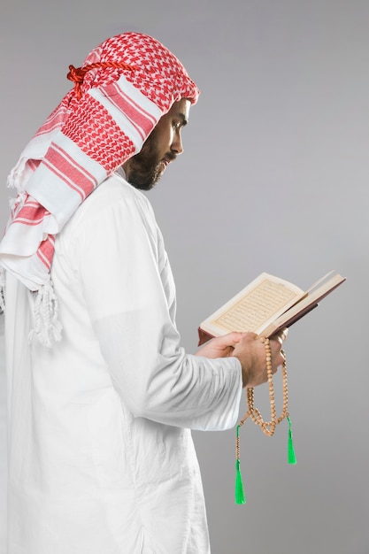 Uomo musulmano che legge dal Corano e che tiene le perle di preghiera
