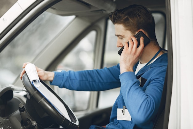 Uomo nel camion. Ragazzo in uniforme da consegna. Uomo con appunti.