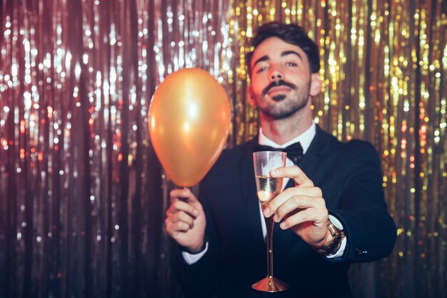 Uomo nel partito di nuovo anno con palloncino e champagne