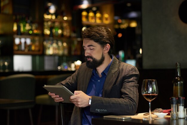 Uomo nel ristorante, leggendo le notizie online