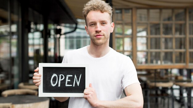Uomo nella caffetteria che tiene segno aperto