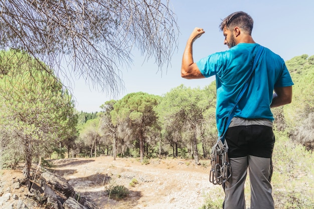 Uomo nella foresta che mostra i muscoli