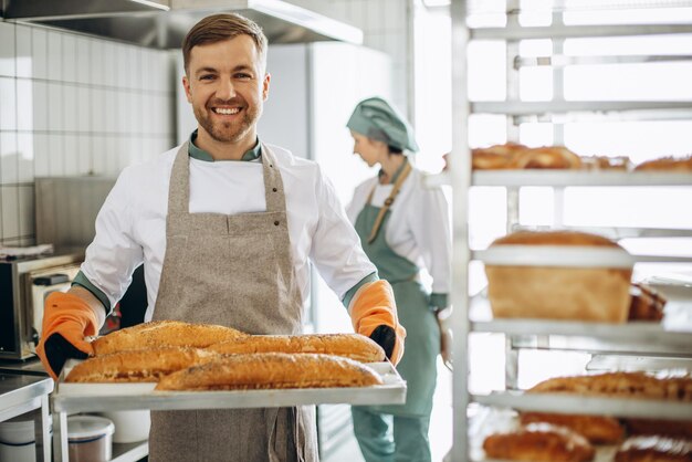 Uomo panettiere con pane fresco a casa del fornaio