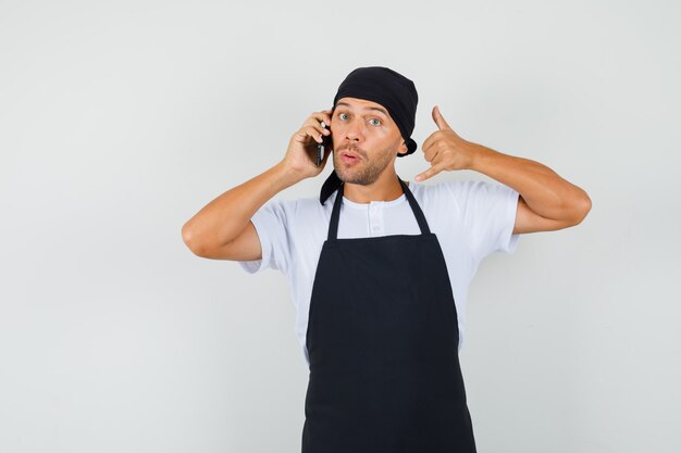 Uomo panettiere in t-shirt, grembiule parlando al cellulare