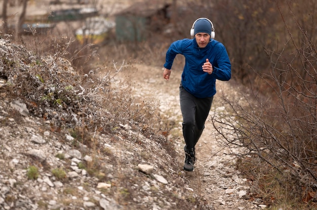 Uomo pieno del colpo che corre sul sentiero in natura