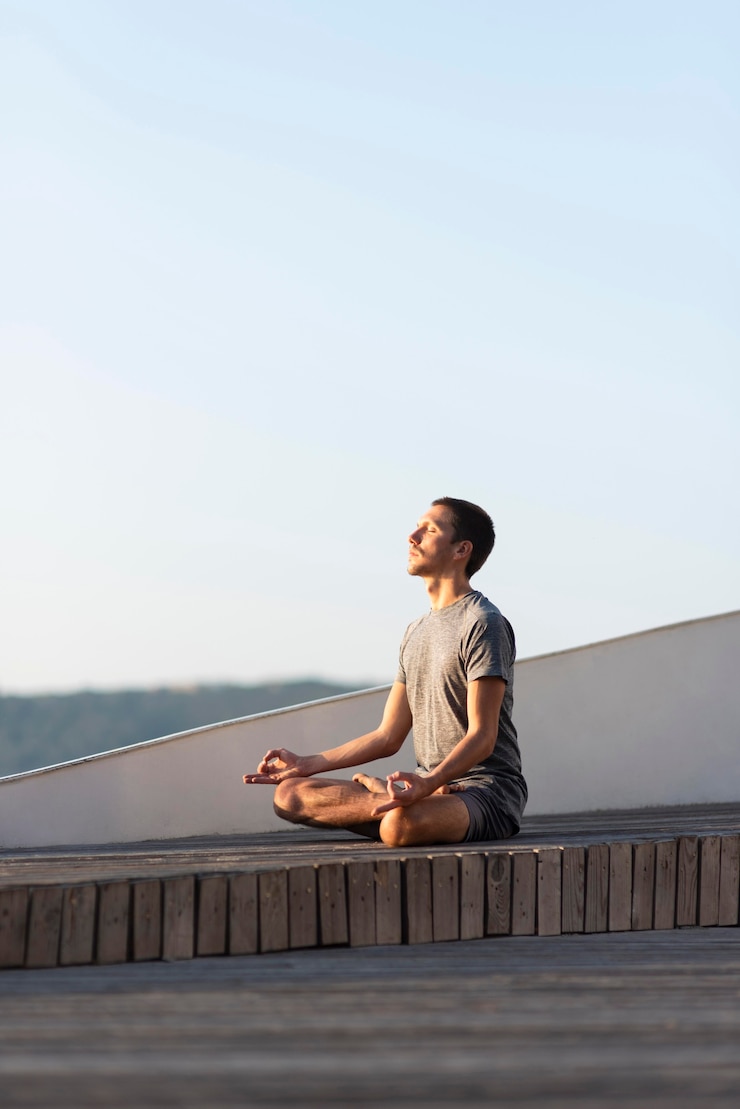 Foto gratuito uomo pieno del colpo che fa la posa di sukhasana all'aperto